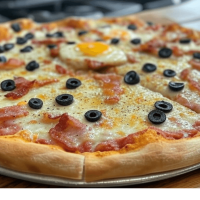 "Dégustez 'La Lulu' chez Pizza Mania à Saint-Yrieix : base crème, olives, fromage, bacon, cheddar et œuf pour un plaisir gourmand."